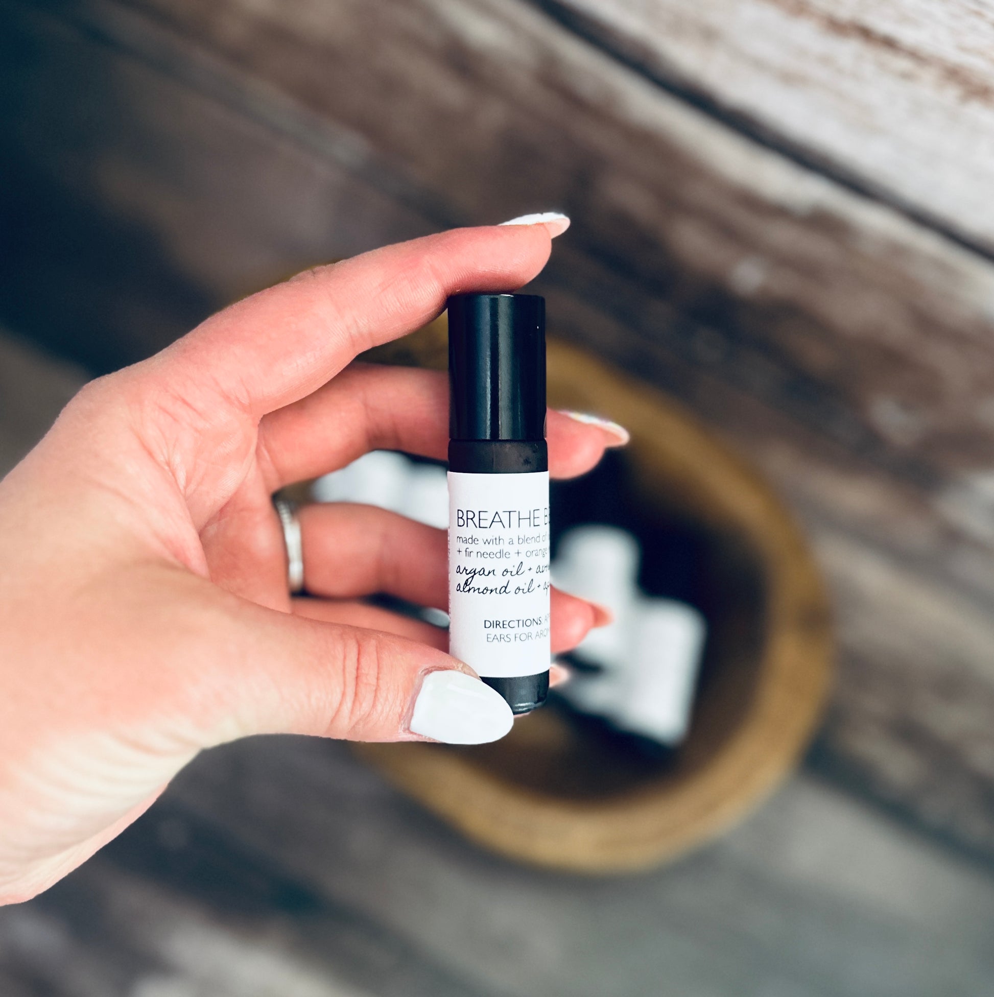 a hand holding a bottle of breathe essential oil