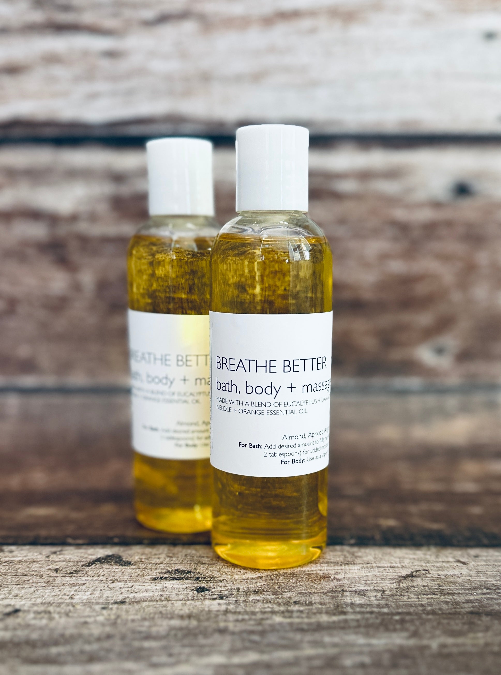 two bottles of bath and body oil on a wooden surface