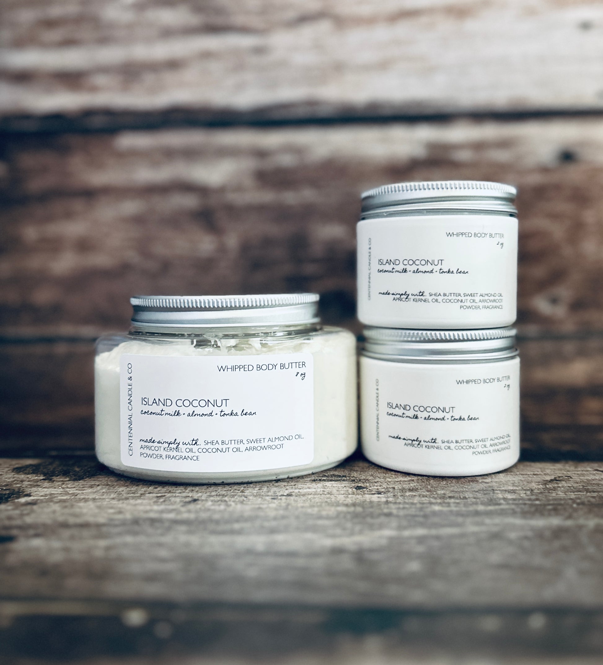 three jars of handmade body butter sitting on a wooden surface